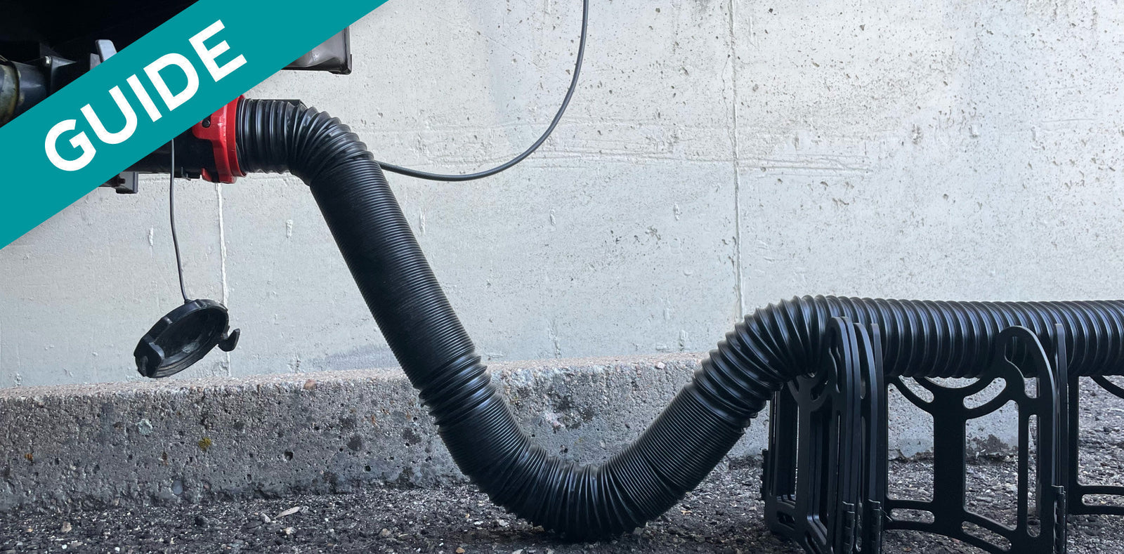 RV sewer hose with a P-trap fitting attached to a concrete wall and drainage system.