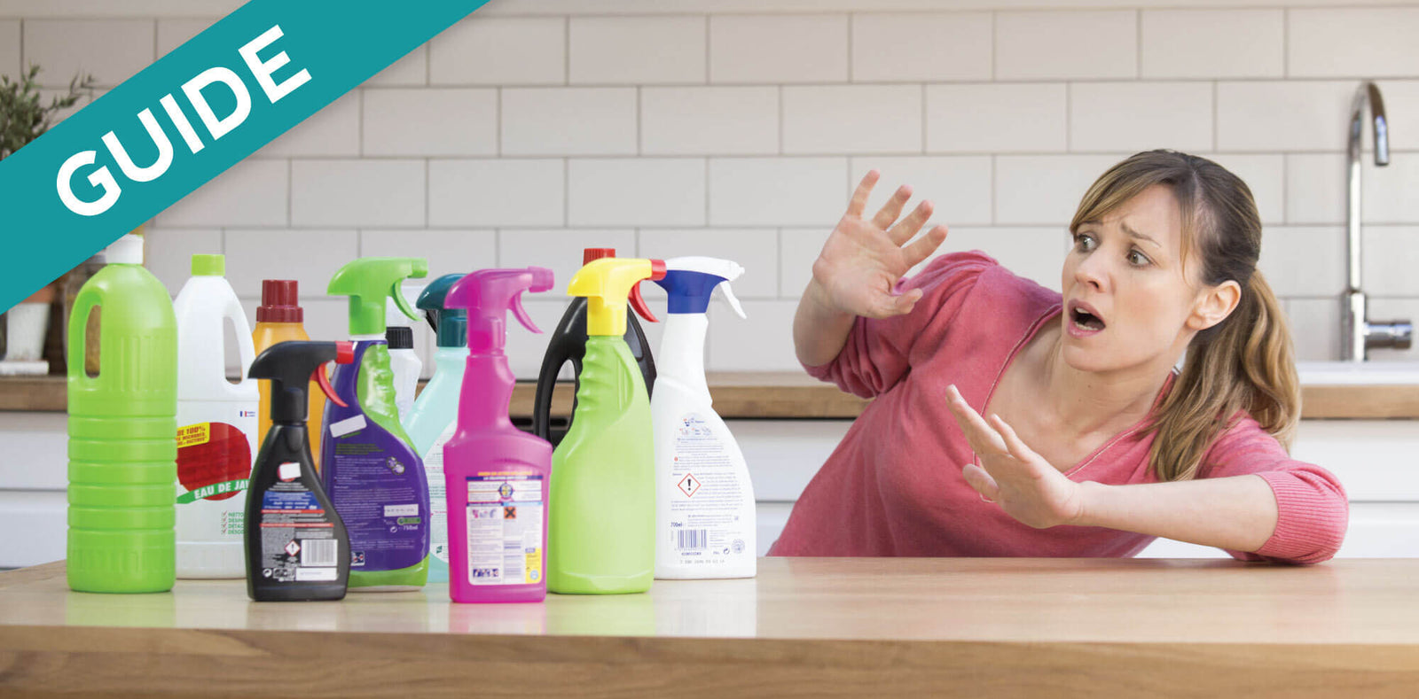 Woman recoils from an array of colorful cleaning spray bottles on a counter.