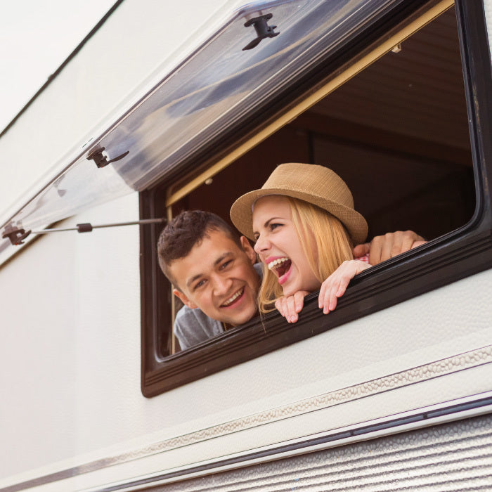 Elated couple leaning out of an RV window.