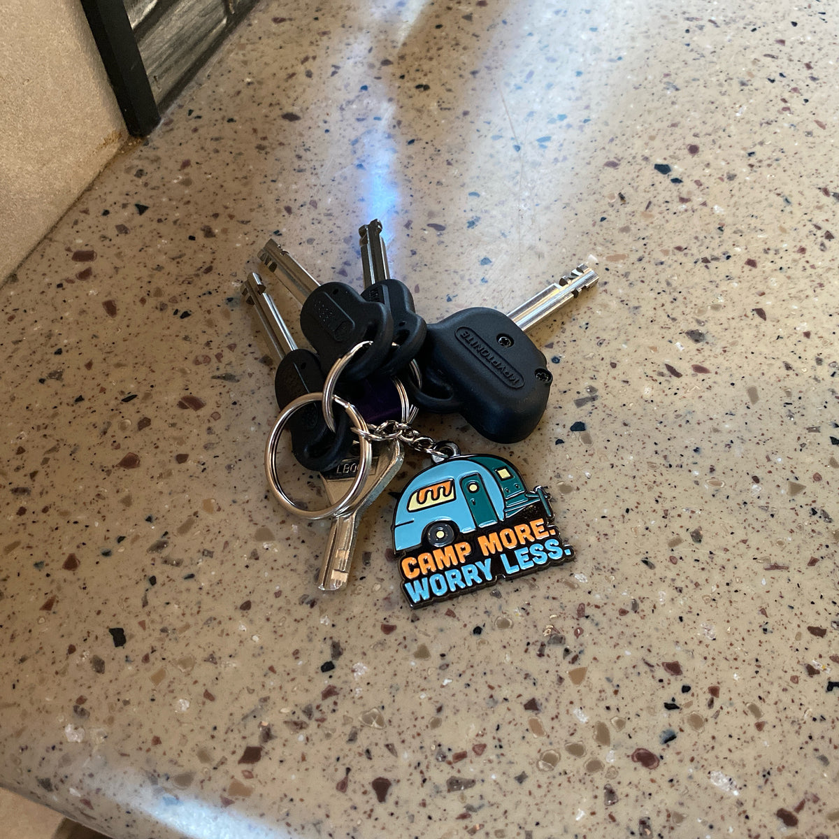 Camp More. Worry Less. Trailer Keychain on kitchen countertop. Unique Camping + Marine